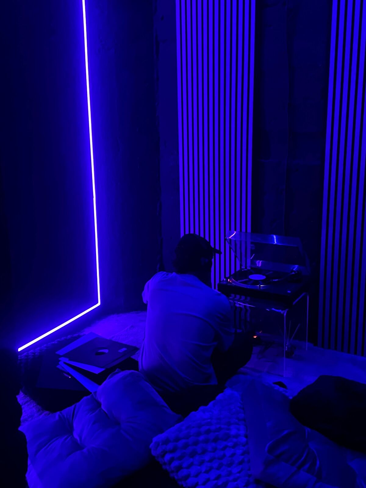 Listener at a turntable in a room lit in deep blue