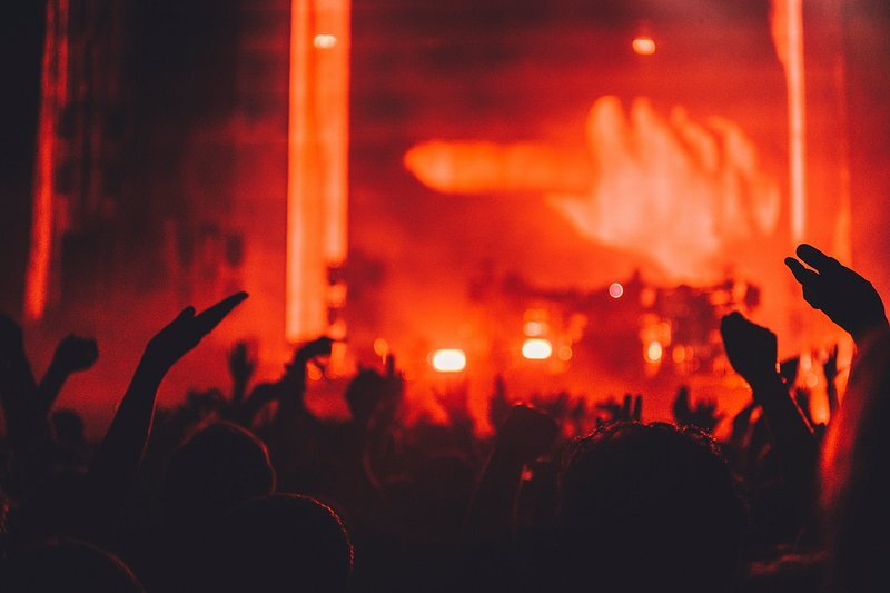 Crowd with raised hands in front of a stage bathed in red light